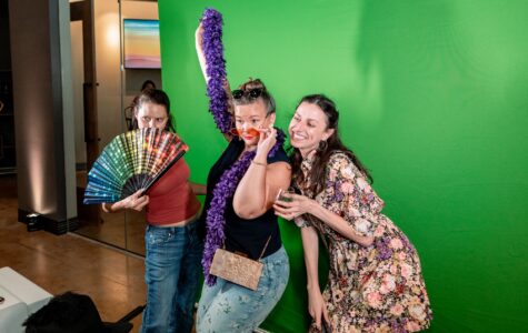 Three women pose infront of a green screen in a photobooth at a company event